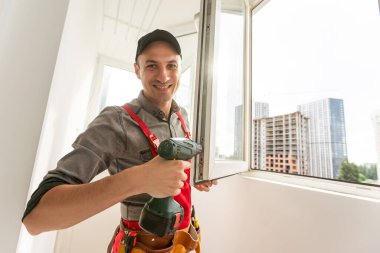 İnşaat işçisi pencereyi içeri yerleştirirken matkap kullanıyor. Yüksek kalite fotoğraf