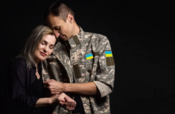Happy Ukrainian couple who met after the war. A military man in uniform hugs his happy wife.