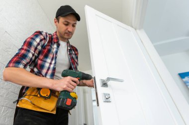 Marangoz kapı kilidini tamir ediyor. Kapı kolu takıyorum. Yüksek kalite fotoğraf