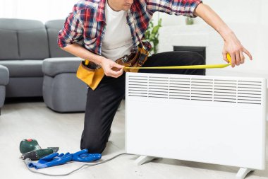 Beyaz yenilenmiş oturma odasındaki pencerenin yanına su ısıtma kaloriferi monte eden işçi, fotokopi alanı olan bir görüntü. Yüksek kalite fotoğraf