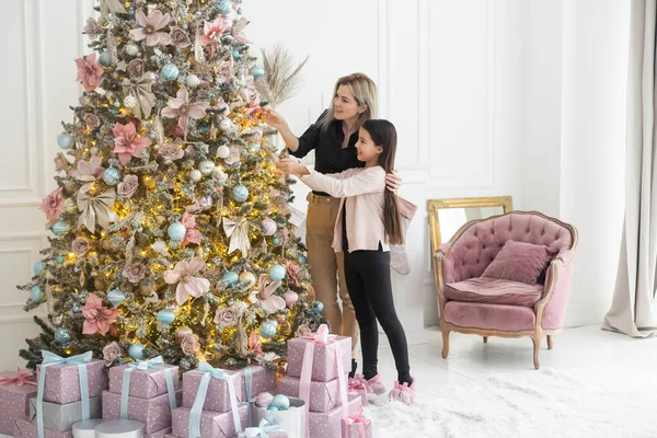 Anne ve kızı Noel ağacını birlikte süsler. Bir çocuk odasının şık bir iç mekanı. İskandinav eko-tarzı dekor. Yeni yıl kutlaması. Noel arifesi. Ortak zaman yönlendirmesini destekleyin. Aşk