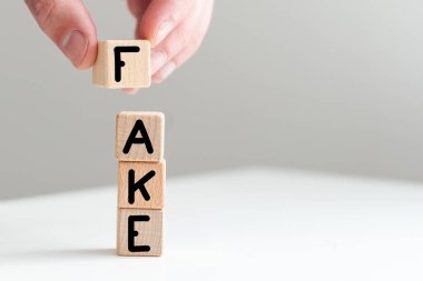 Tahta bloklara yazılmış sahte kelime, masasının önünde elinde kalem ve defterle oturan bir adam. Yüksek kalite fotoğraf