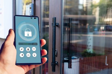 ekranda siyah mobil akıllı telefon akıllı evine uygulamasıyla tutan el. arka plan bulanık ev. Tüm ev denetimleri ve ev güvenlik bakımı için erişim.