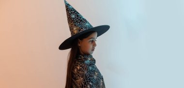 halloween child in witch hat look like wizard school pupil, happy halloween holiday