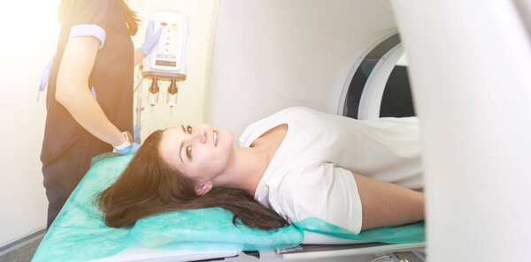 Технолог компьютерной томографии с видом на пациента в компьютерном томографе во время подготовки к процедуре. Пациентка на томографии