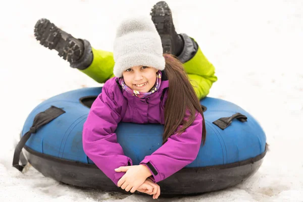 一个活泼的女孩坐着雪管滑下山 可爱的小快乐的孩子在冬天在户外的雪橇上玩得很开心 健康兴奋的孩子拖着雪地下山 一家人过冬 — 图库照片