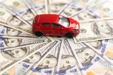Kırmızı oyuncak araba dolar banknotlarının üzerinde duruyor. Araba, benzin, sigorta ve diğer araba maliyetleri. Yüksek kalite fotoğraf