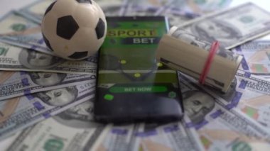 Futbol Dünyası Konsepti. Top ve akıllı telefon, dolar banknotları ve yeşil arka plan üzerine bahis uygulaması. Futbol kumarı para konsepti. Yüksek kalite fotoğraf