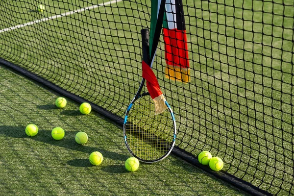 Tennis court Top view Six tennis balls and racket on the green grass background. High quality photo