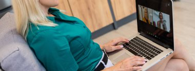 Evde video konferansı için dizüstü bilgisayar kullanan genç bir kadının kırpılmış görüntüsü.