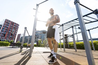 Bir adam egzersiz makineleriyle sokakta antrenman yapıyor..