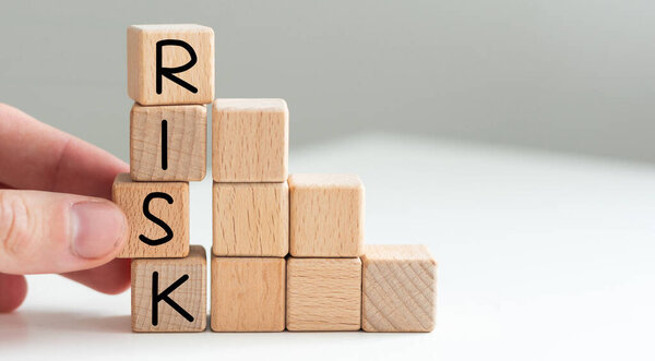 Financial risk assessment, risk reward and portfolio risk management concept. Blocks of wood cubes arranged creatively to depict the concept. Letters R, I, S, K on cubes. High quality photo