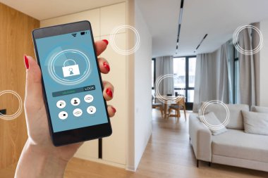 Elinde akıllı telefon tutan ve evinde güvenlik uygulaması olan genç bir kadın. Ev güvenliğini mobil bir cihazdan kontrol etme ve yönetme kavramı.