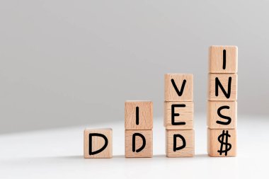 Hisse senedi grafiği ve dolar arkaplanlı harf küpü üzerindeki temettü kelimesinin kavramsal görüntüsü. Yüksek kalite fotoğraf