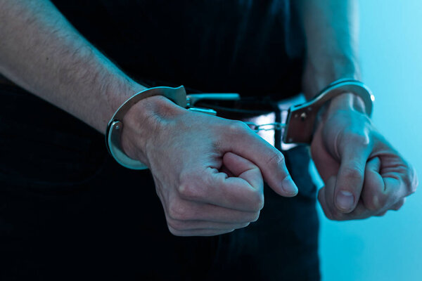 Мужские руки в наручниках черный фон. Высокое качество фото