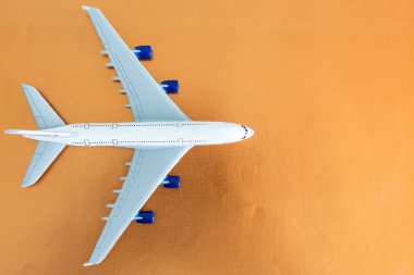 Turuncu arka planda uçak, düz yatış, seyahat konsepti.