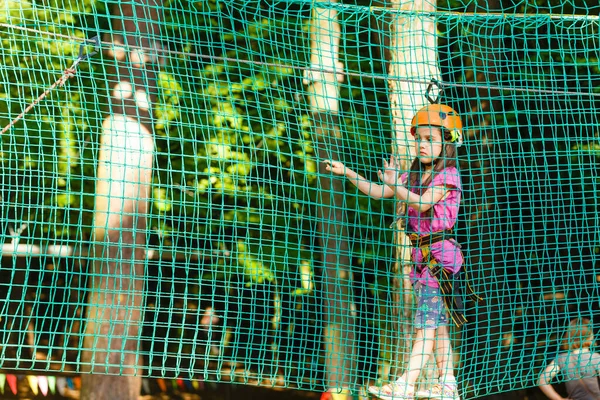 一个快乐的小女孩在一个木制背景的缆绳公园里 — 图库照片