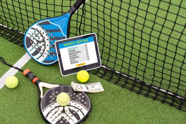 Tablet bilgisayar, para ve arka planda tenis roketi. Spor bahsi kavramı. Yüksek kalite fotoğraf