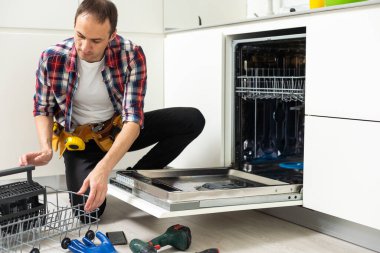 Mutfaktaki bulaşık makinesini tamir eden bir işçi. Yüksek kalite fotoğraf
