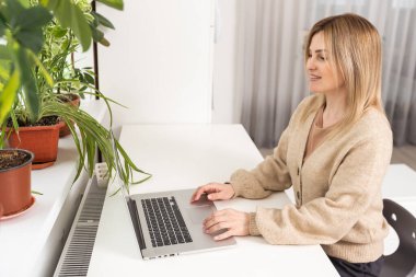 Dizüstü bilgisayarda çalışan kadınların üst görüntüsünü kapatın. Aile harcamalarını düzenek kullanarak yönetin. Ev hanımı mali hesaplarla meşgul olsun.