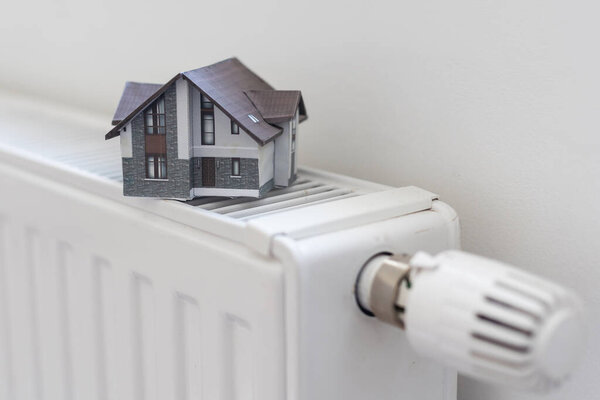 Model of house on white radiator. High quality photo