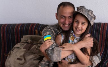 Ukrayna askeri üniformalı asker kızına sarılıyor. Aile toplantısı.