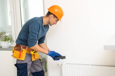 İş yerindeki tesisatçı. Su ısıtma radyatörü kuruluyor.