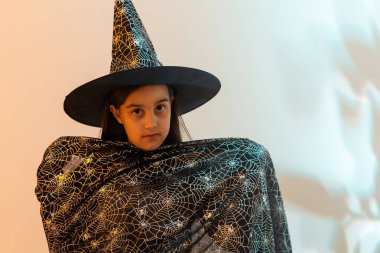 halloween child in witch hat look like wizard school pupil, happy halloween holiday