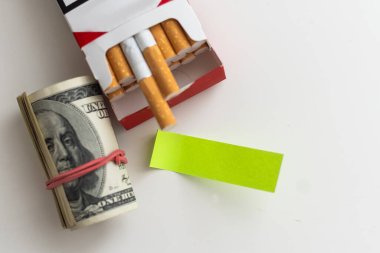 Gri arka planda 100 dolarlık banknotlara sarılı sigaralar. Sigara fiyatlarında sürekli artış kavramı. Yüksek kalite fotoğraf