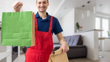 Paket çantalı yakışıklı teslimatçı büyük bir gülümsemeyle mutlu.