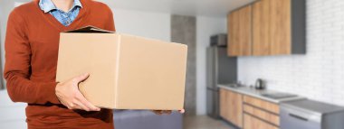 Smiling young delivery man holding and carrying a cardbox.