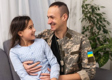 Ukrayna askeri üniformalı asker kızına sarılıyor. Aile toplantısı.
