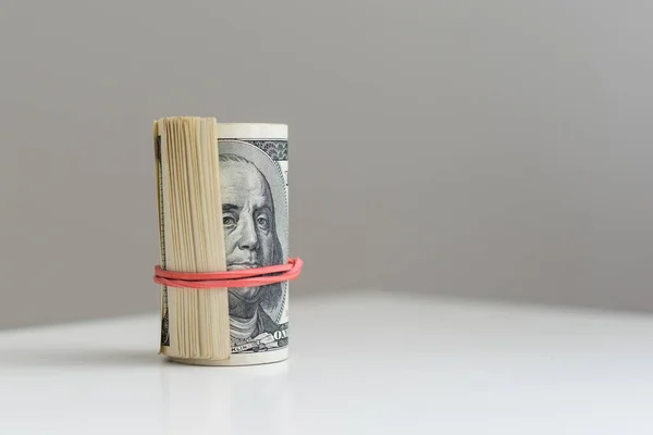 A vertical closeup of a roll of money on light gray background . High quality photo