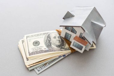 Tahta ev modeli Amerikan doları banknotlarının arka planında. Konut piyasası, emlak satın alma veya kiralama. Gayrimenkul alıp satma kavramı.