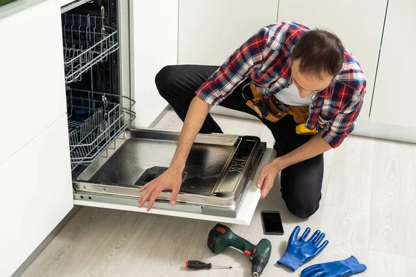 Master installing the dishwasher in a kitchen cabinet. High quality photo