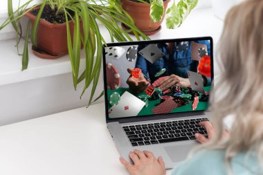 Online kumar, bahis konsepti. Poker fişleri, dizüstü bilgisayarda kumarhane ruleti ve telefon ekranları. Bilgisayarla çalışan ve elinde akıllı telefon tutan bir adam, ofis geçmişi. Yüksek kalite fotoğraf
