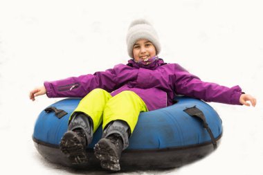 Aktif kız kar tüpüyle tepeden kayıyor. Sevimli küçük mutlu çocuk kışın kızakla dışarıda eğleniyor. Sağlıklı, heyecanlı çocuk karlı yokuş aşağı iniyor, aile kışı.