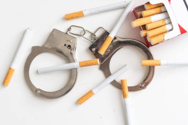 Ben bir sigara rehinesiyim. Kırık sigaraları kül tablasına koy. Yanında sigaralar kelepçelere bağlı. Yüksek kalite fotoğraf