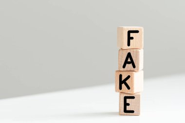 Beyaz finansal tabloların arka planında sahte sözcüğü olan dört tahta küp, güçlü bir iş konsepti. gri arka plan. Yüksek kalite fotoğraf