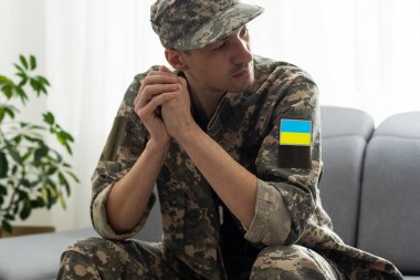 Üzgün bir asker evde oturup düşünüyor.