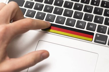 Online International Business concept: Computer key with the Germany flag on it. Male hand pressing computer key with Germany flag.