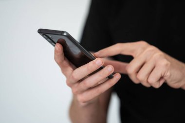 Adam işaret parmağı, telefon ekranını araklıyor. Erkek sosyal medyayı kontrol ediyor, interneti yönetiyor, fotoğrafları, web sayfalarını ve haber makalelerini inceliyor. Yüksek kalite fotoğraf. Yüksek kalite fotoğraf