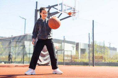 Yaz sezonunda sahada basketbol oynayan bir kız..