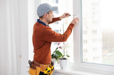 Evdeki oturma odasına plastik pencereler monte eden ya da ayarlayan işçi.
