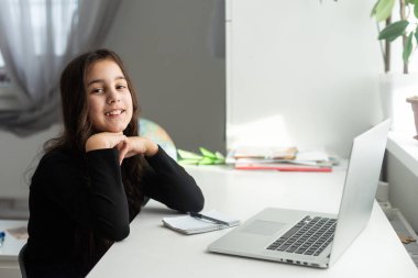 Latin Latin üniversiteli kız üniversite masasında oturmuş dizüstü bilgisayarla online eğitim alıyor. Sanal eğitim webinar, uzaktan eğitim, uzak akademik öğrenim