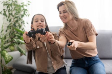 Mutlu bir aileyiz. Anne ve kız çocuğu video oyunu oynuyorlar. Aile rahatlar