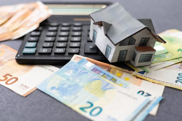 The concept of mortgage and rental housing and real estate. Mortgage credit lending. House of euro bills on the plan of the house and laid out dollar banknotes on a blue background. High quality photo