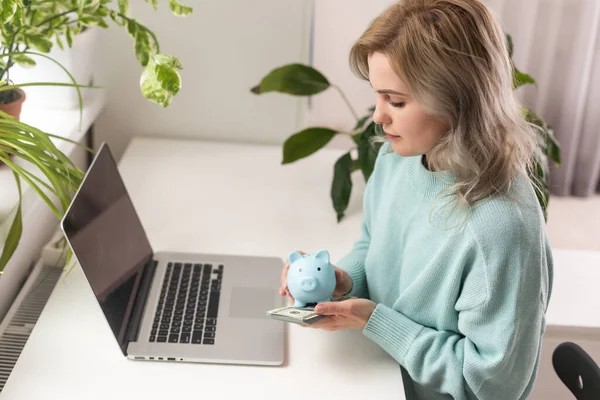 Young woman planning save salary money early years using laptop computer with pig bank save coin