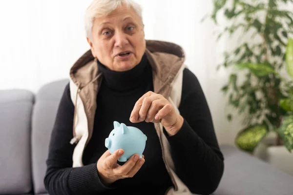 Close-up shot of elderly woman holding pig money-box. Senior woman hands holding a piggybank. Concept of saving money for old age