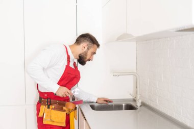 Tesisatçı mutfak musluğu kuruyor. Apartman yenileniyor.